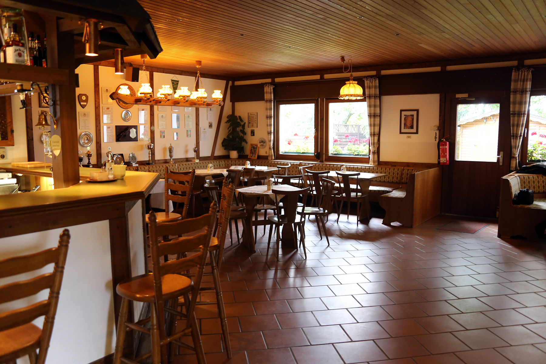 Ein Clubhaus mit Terrasse, umgeben von Bäumen und viel Natur.